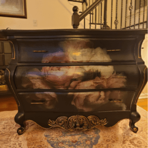 A black dresser with some painting on it