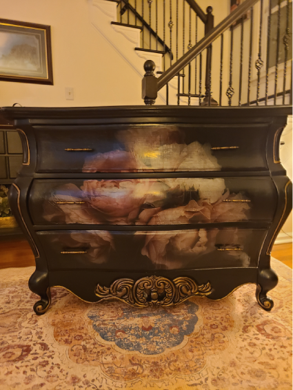 A black dresser with some painting on it