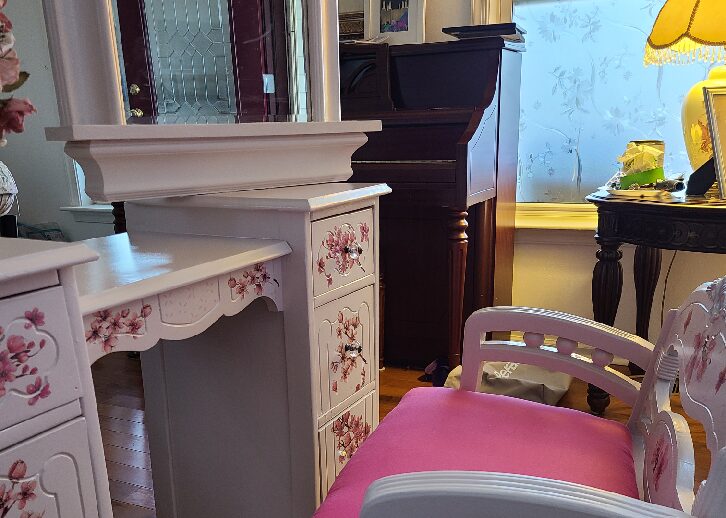 A pink chair and white desk in front of a mirror.