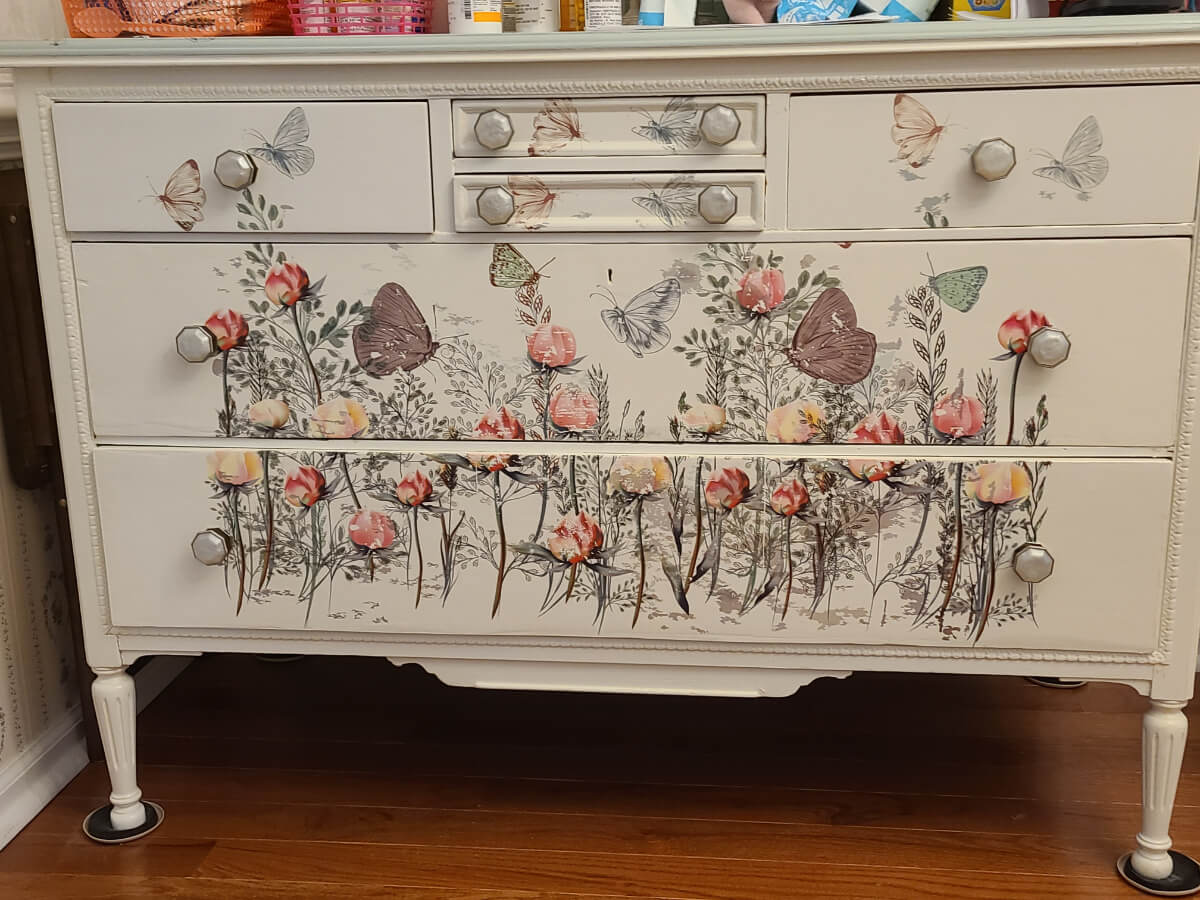 A dresser with flowers and butterflies on it.