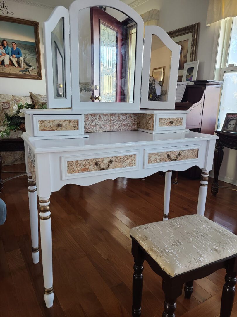 A white vanity with three mirrors and two drawers.