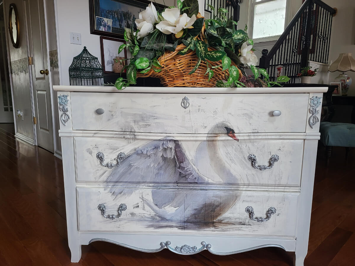 A white dresser with swans painted on it