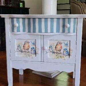 A white cabinet with blue stripes and birds on it.