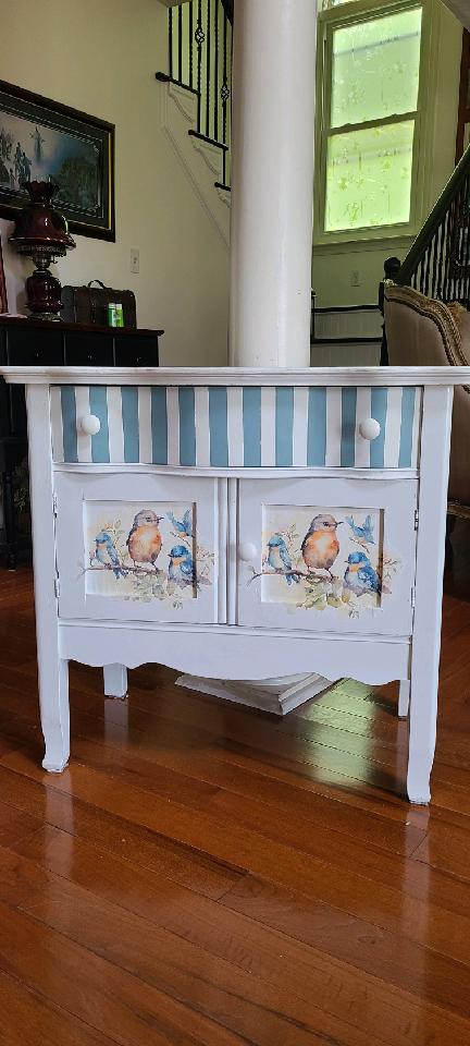 A white cabinet with blue stripes and birds on it.