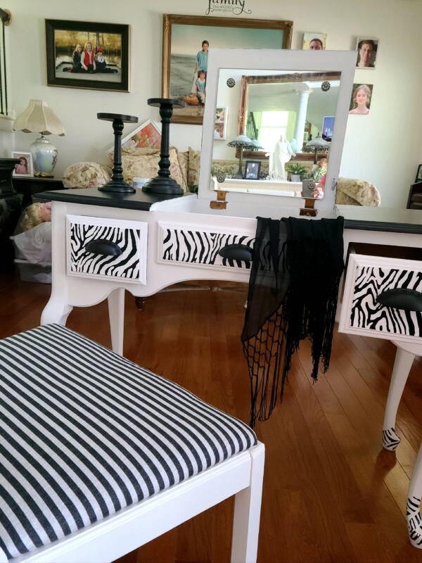 A zebra print dresser and chair in the corner of a room.