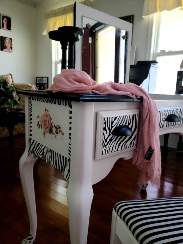 A zebra print table with pink scarf on top of it.