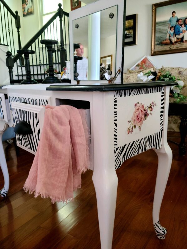 A pair of zebra print tables with pink roses on the top.