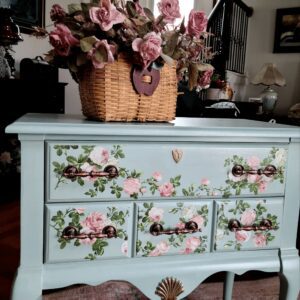 A blue dresser with flowers painted on it