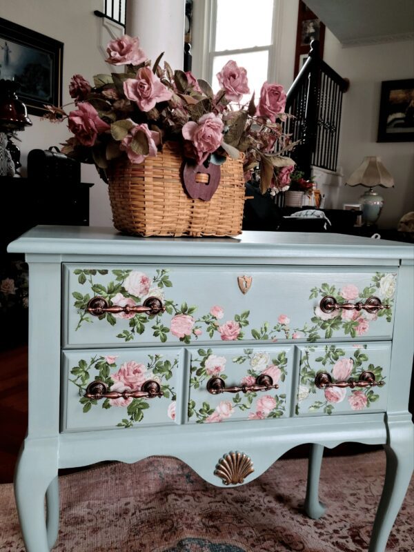 A blue dresser with flowers painted on it