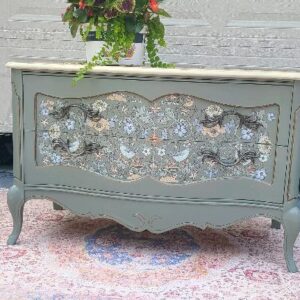 Grey dresser with floral pattern on drawers.