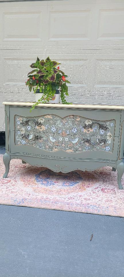 Grey dresser with floral pattern on drawers.