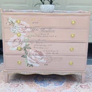 Pink dresser with floral design and gold accents.