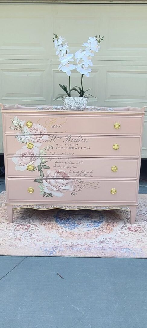 Pink dresser with floral design and gold accents.